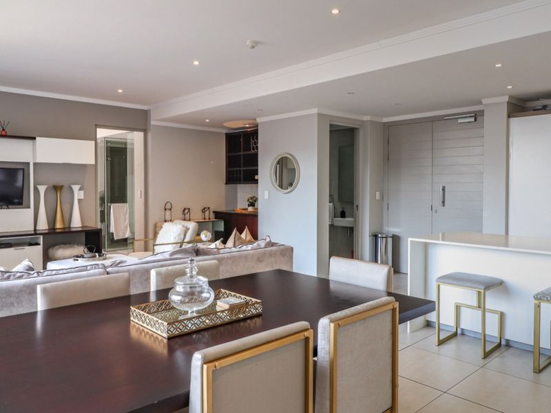 A spacious open-plan living and dining area featuring tiled floors, recessed lighting, and a modern kitchen island with integrated cabinetry.