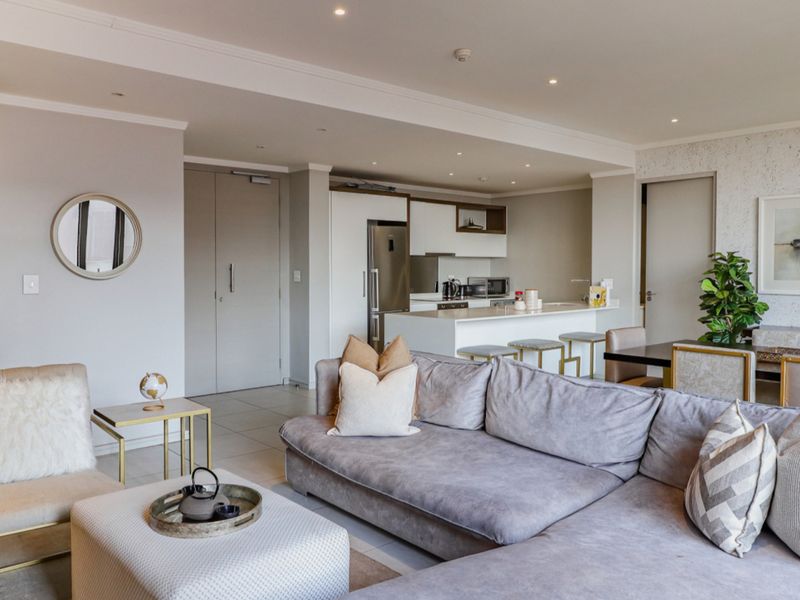 A spacious open-plan living and kitchen area featuring modern cabinetry, a central island, recessed lighting, and neutral finishes throughout.