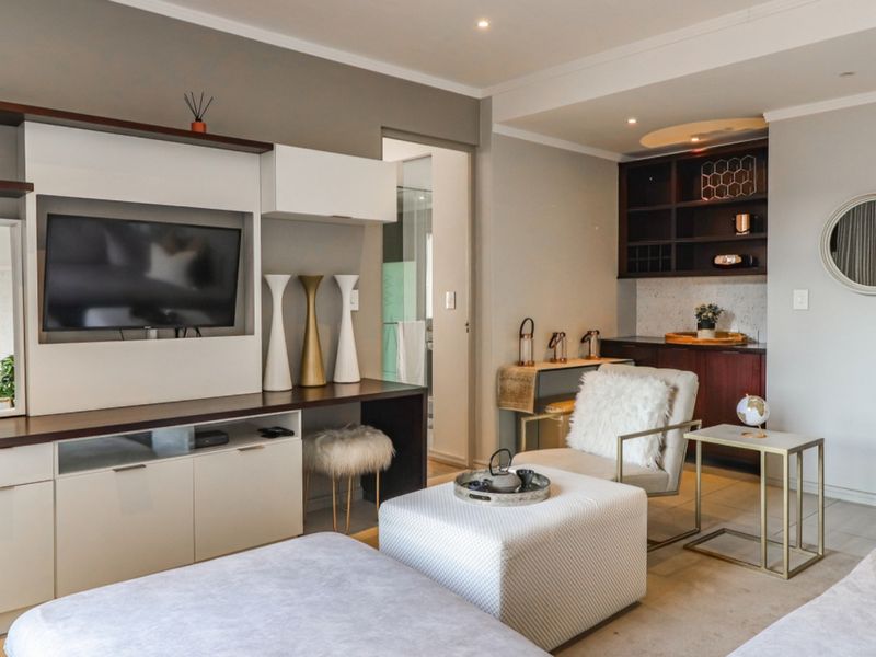 A well-maintained living area featuring built-in cabinetry, integrated shelving, recessed lighting, and neutral tiled flooring, offering a clean and functional space.