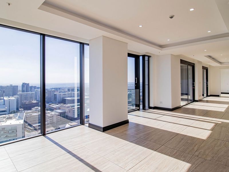 Spacious, modern open-plan living area featuring floor-to-ceiling windows with expansive city views, recessed lighting, and neutral tiled flooring.