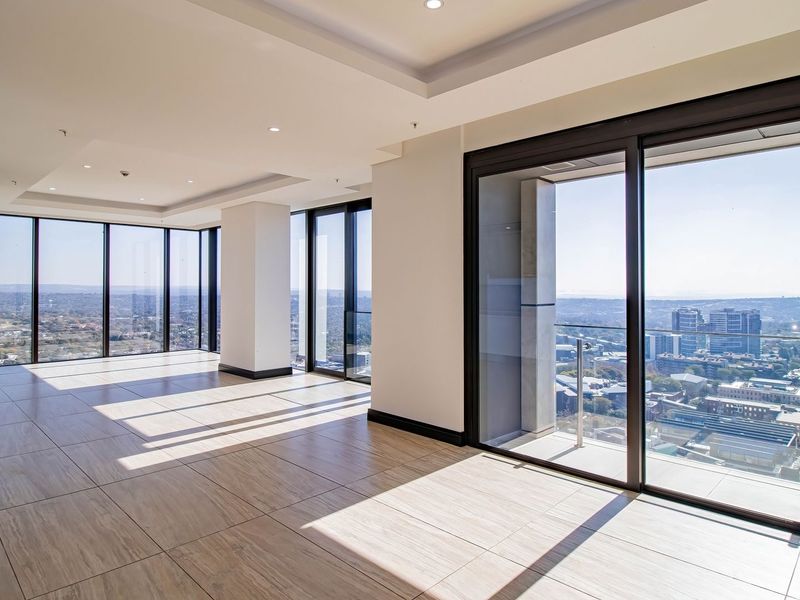 Spacious, light-filled open-plan living area featuring large format floor tiles, recessed lighting, and expansive floor-to-ceiling windows with panoramic city views.