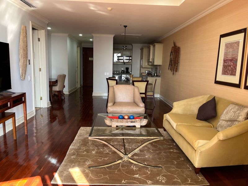 Open-plan living area featuring polished hardwood floors, crown molding, and a compact kitchen with integrated cabinetry and laundry facilities.