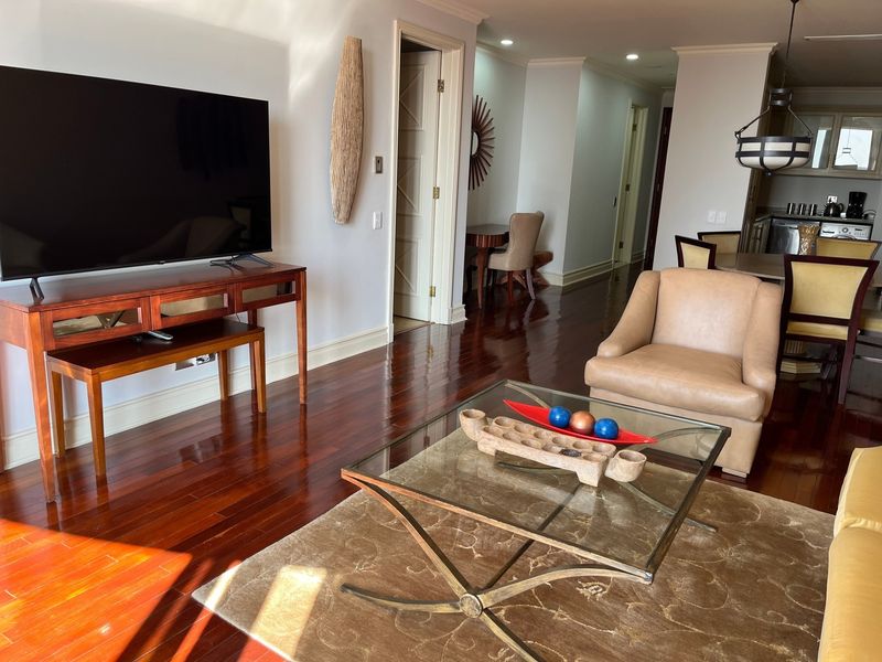 An open-plan living and dining area featuring polished hardwood flooring, recessed lighting, and neutral wall finishes, providing a spacious and connected layout.
