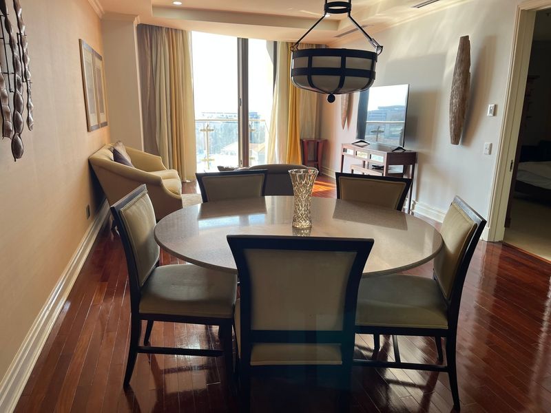 Spacious open-plan living and dining area featuring polished hardwood flooring, recessed ceiling details, and direct access to a private balcony.