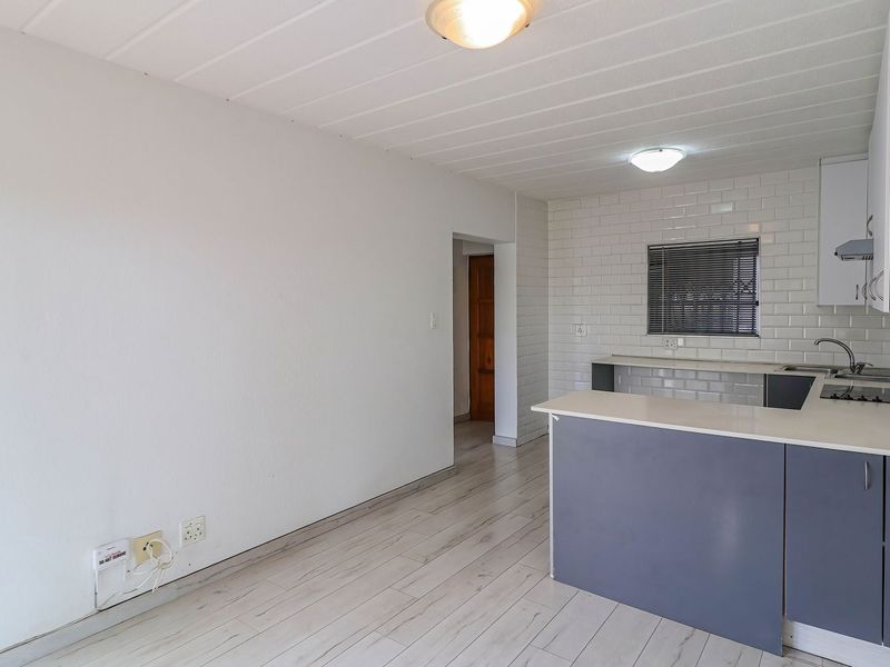 Bright open-plan kitchen and living area featuring modern subway tile backsplash, laminate flooring, and a functional breakfast bar layout.