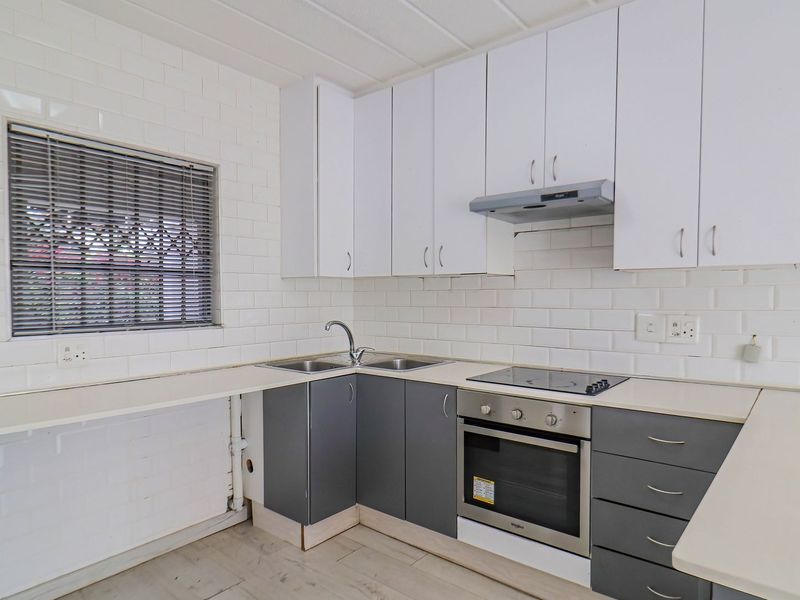 A clean, functional kitchen featuring white upper cabinets, grey lower cabinetry, subway tile backsplash, and integrated stainless steel appliances.