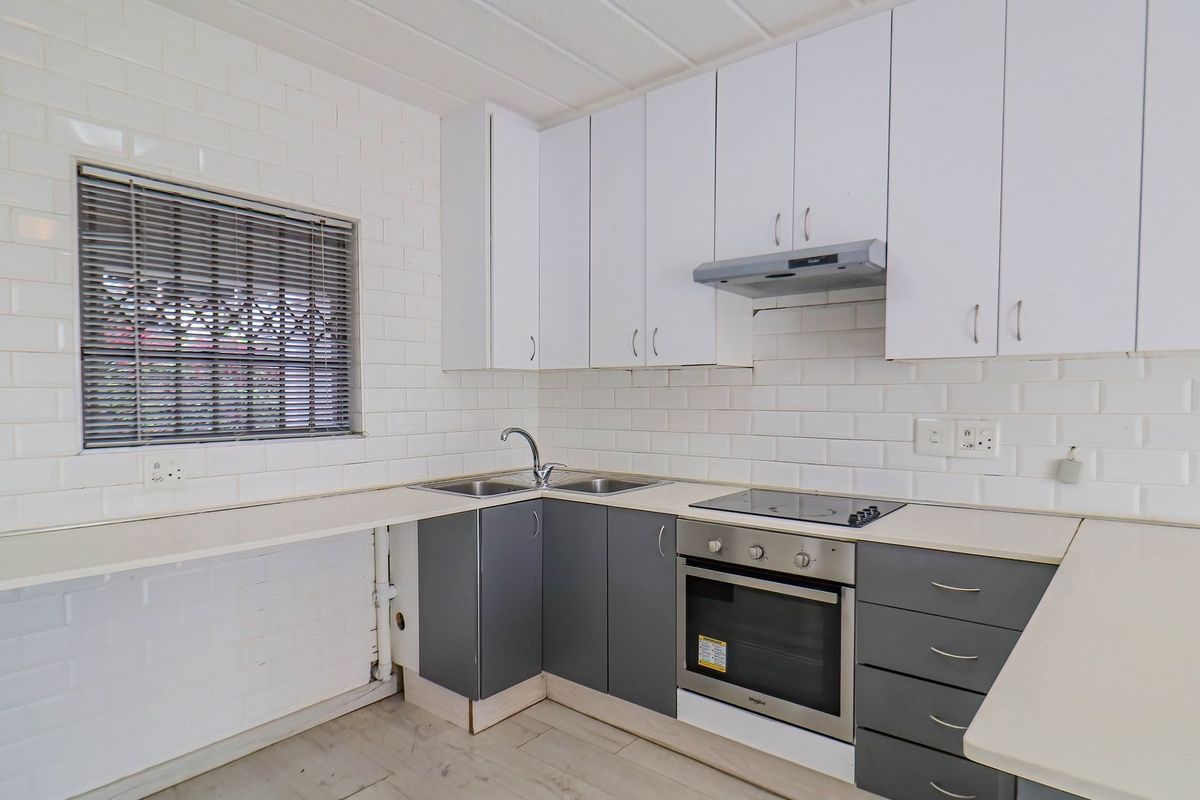 A clean, functional kitchen featuring white upper cabinets, grey lower cabinetry, subway tile backsplash, and integrated stainless steel appliances.