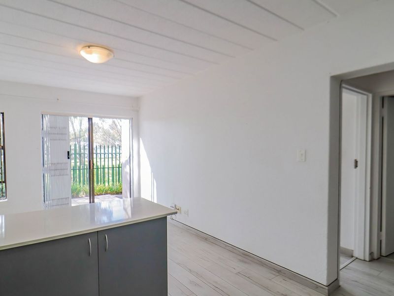An open-plan living area featuring laminate flooring, a kitchen island, and a sliding glass door leading to an outdoor space.