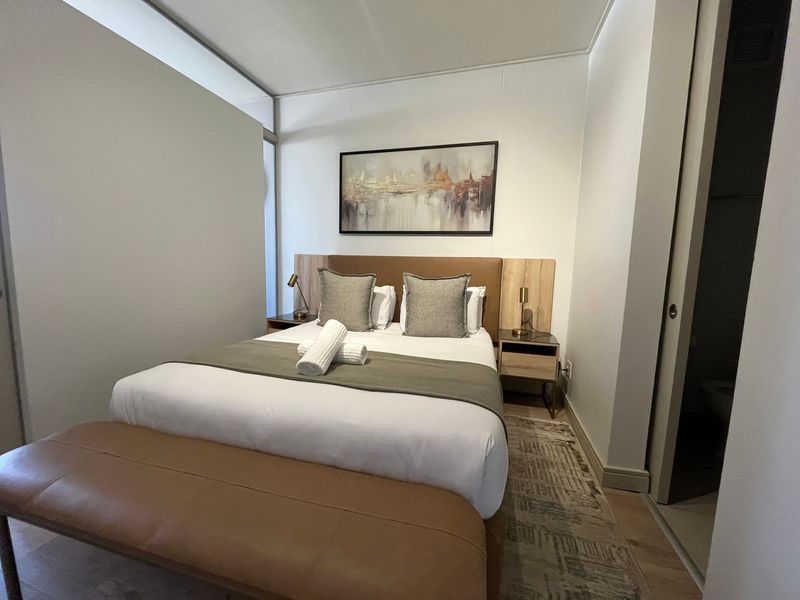 A well-maintained bedroom featuring laminate flooring, a built-in headboard, and neutral finishes, providing a comfortable and modern living space.