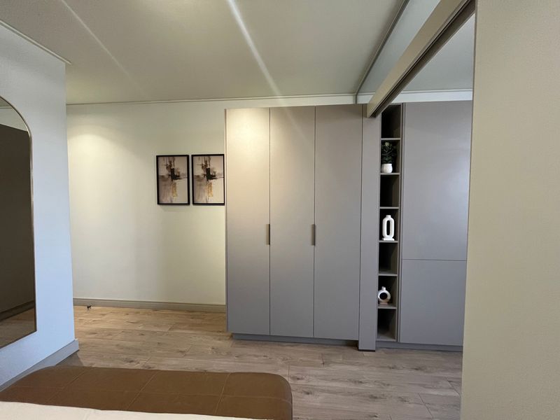 A modern bedroom featuring high-quality built-in wardrobes with integrated shelving and durable laminate flooring.