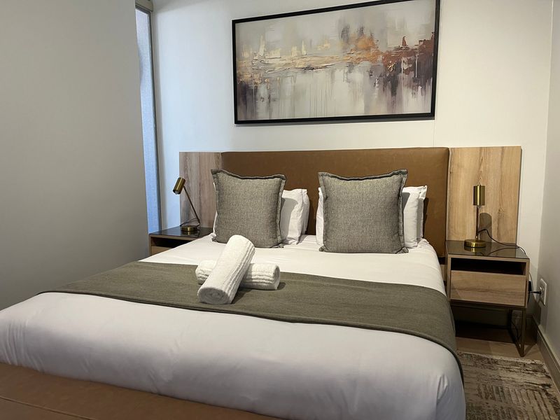 A well-maintained bedroom featuring a modern built-in headboard with integrated bedside tables and contemporary finishes.
