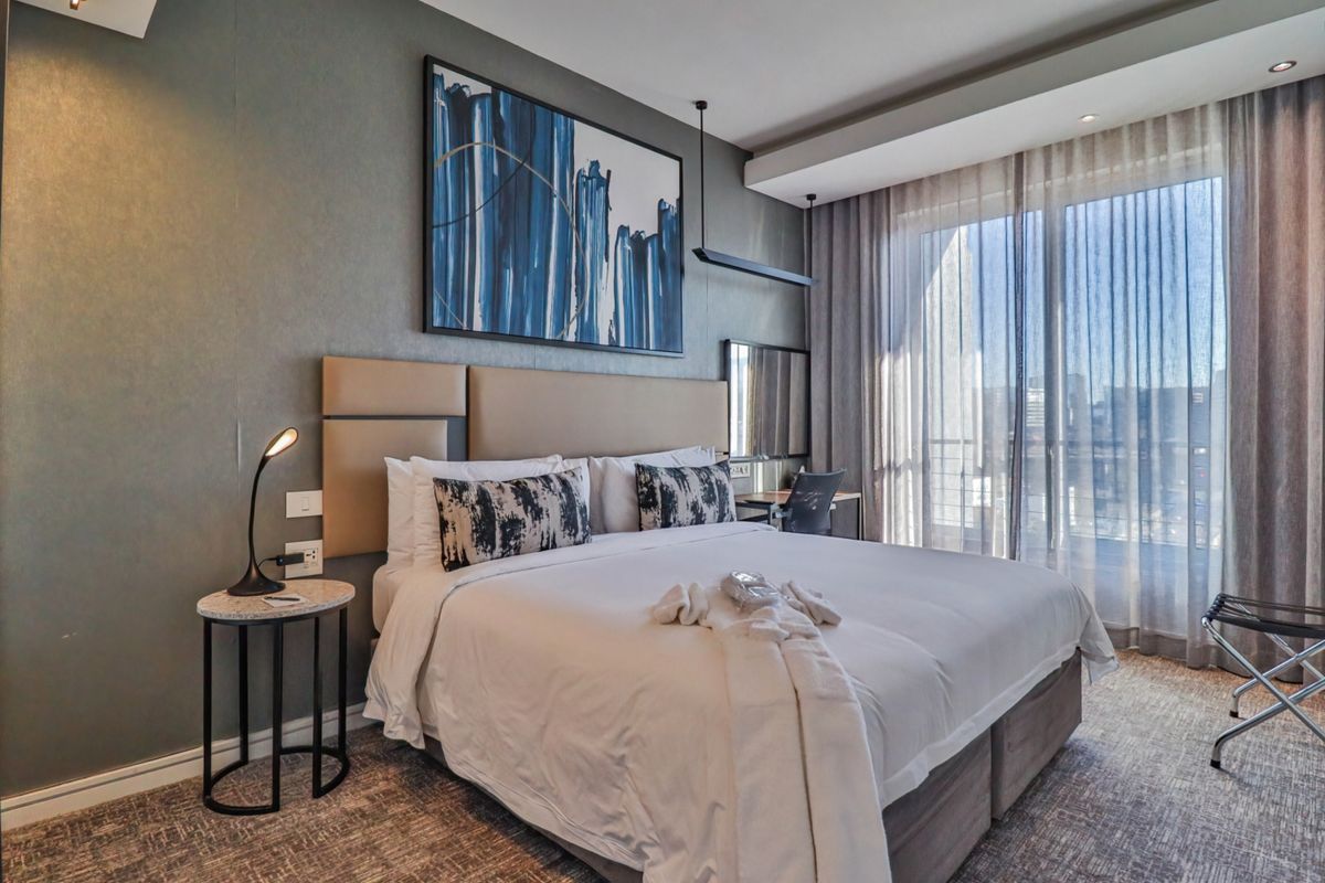 A modern, well-maintained bedroom featuring an upholstered headboard, recessed lighting, and large sliding glass doors that provide ample natural light.