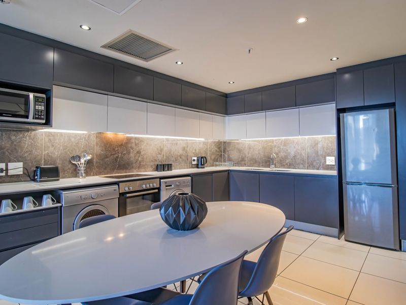 Modern kitchen featuring sleek two-tone cabinetry, stone-look backsplash, integrated appliances, and recessed lighting, offering a contemporary and functional culinary space.