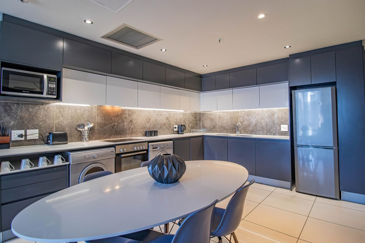 Modern kitchen featuring sleek two-tone cabinetry, stone-look backsplash, integrated appliances, and recessed lighting, offering a contemporary and functional culinary space.