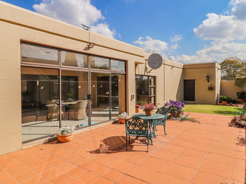 A spacious rear patio featuring terracotta tiling, large sliding glass doors providing indoor-outdoor flow, and a well-maintained garden area.