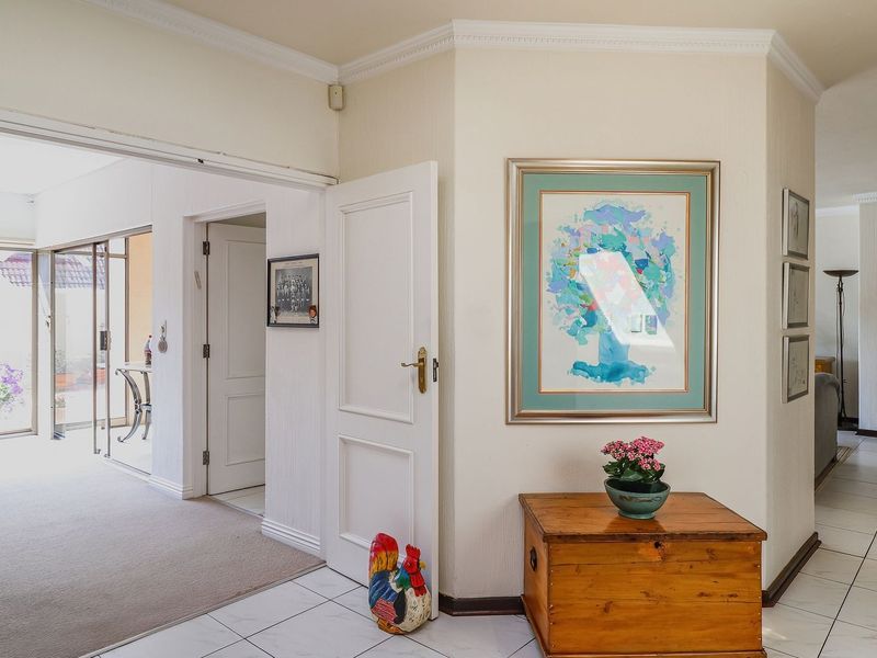 A bright and spacious hallway featuring tiled and carpeted flooring, crown molding, and recessed lighting, providing access to multiple rooms within the home.