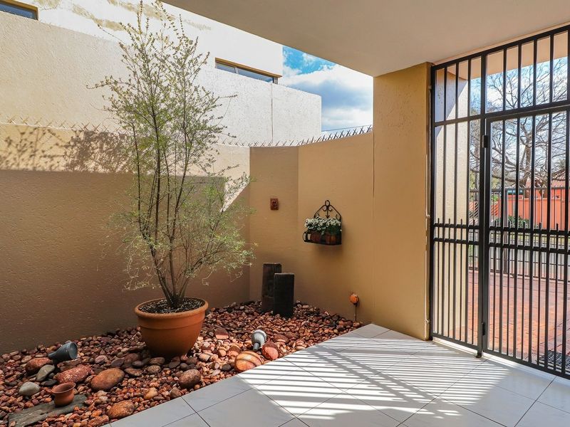A covered patio area featuring tiled flooring and a secure metal gate, providing a private outdoor space.