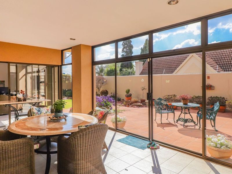 A bright, covered patio area featuring large aluminum sliding doors that open onto a paved outdoor garden space.