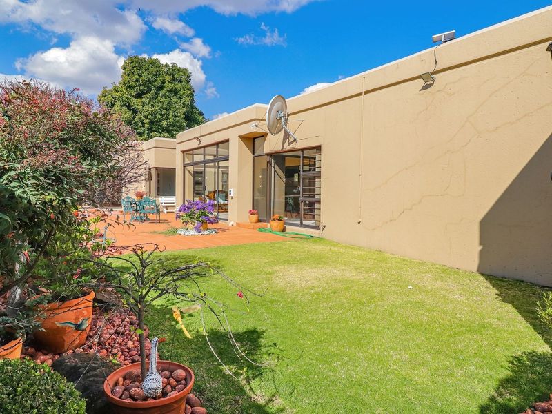 Rear exterior view of the property featuring a paved patio area, manicured lawn, and sliding glass door access to the interior living space.