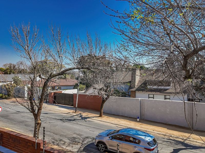 An elevated street view showing the surrounding neighbourhood, featuring brick boundary walls and electric security fencing along the road.