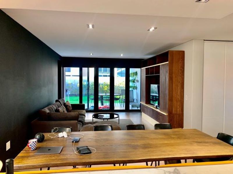Spacious open-plan living and dining area featuring modern recessed lighting, built-in wooden cabinetry, and large sliding glass doors leading to an outdoor patio.