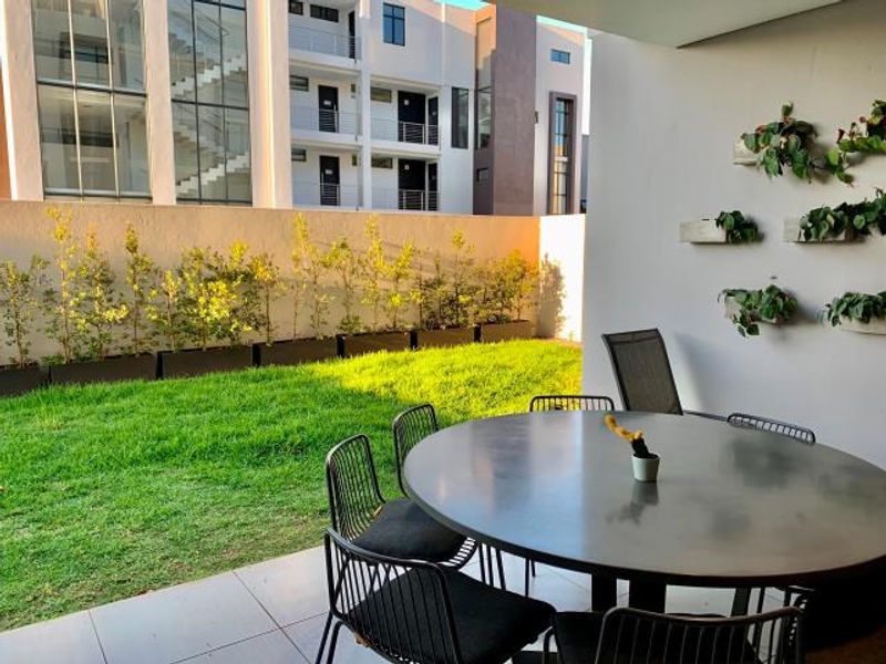 A covered patio area featuring tiled flooring and wall-mounted planters, overlooking a private garden space.
