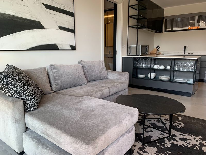 Modern open-plan living area featuring a sleek kitchen with integrated shelving, a central island, and contemporary tiled flooring.