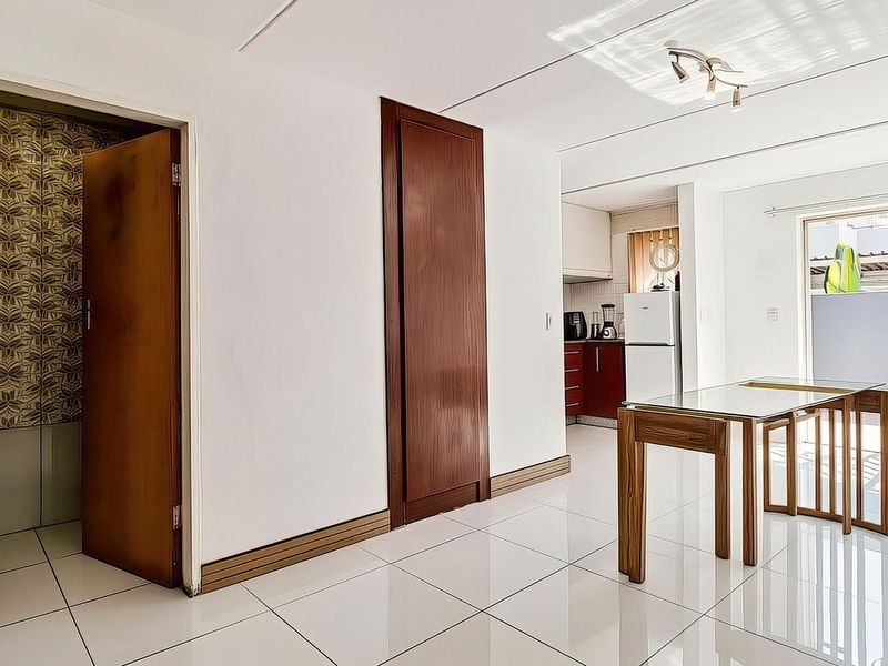 Open plan living area featuring tiled flooring, sliding glass doors to the exterior, and a connected kitchen space with built-in cabinetry.