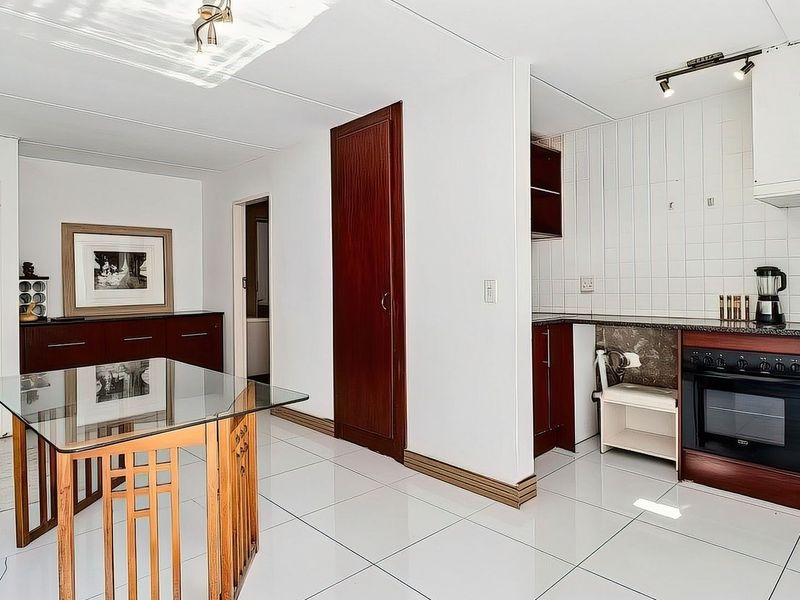 Open-plan living and kitchen area featuring tiled flooring, built-in cabinetry, and integrated oven with hob.