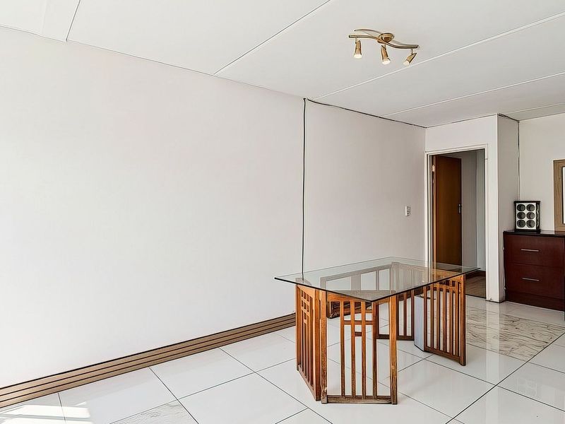 A bright, open-plan living area featuring white tiled flooring and neutral walls, providing a blank canvas for interior design.