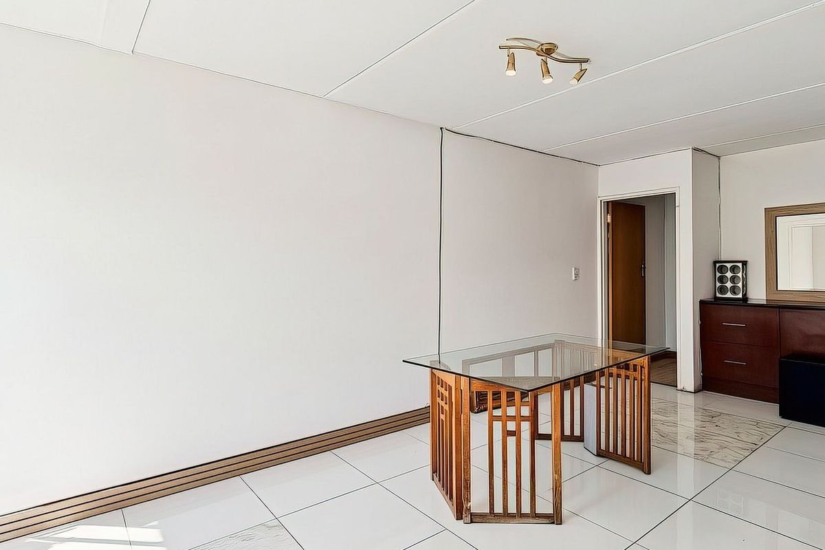 A bright, open-plan living area featuring white tiled flooring and neutral walls, providing a blank canvas for interior design.
