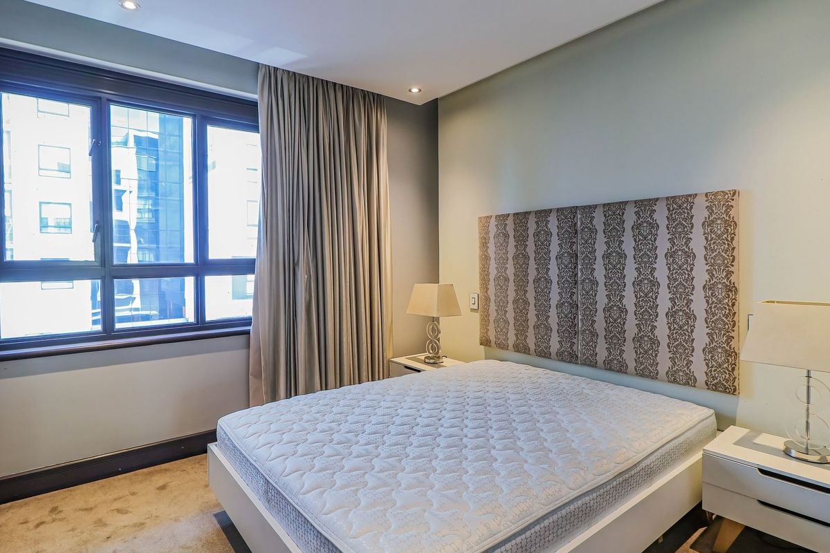 A bedroom featuring recessed ceiling lighting, a large window with curtains, and a neutral wall finish.