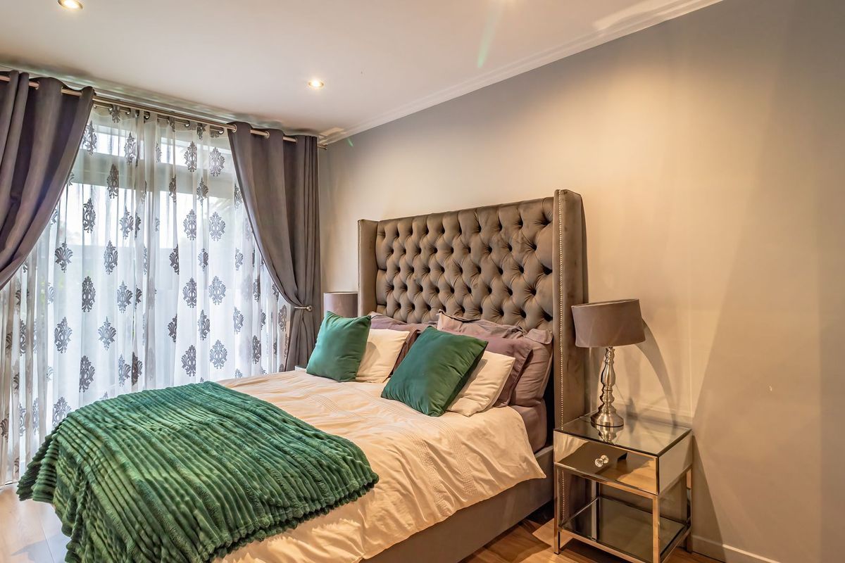 A well-maintained bedroom featuring laminate flooring, recessed downlighting, and a sliding glass door providing natural light.