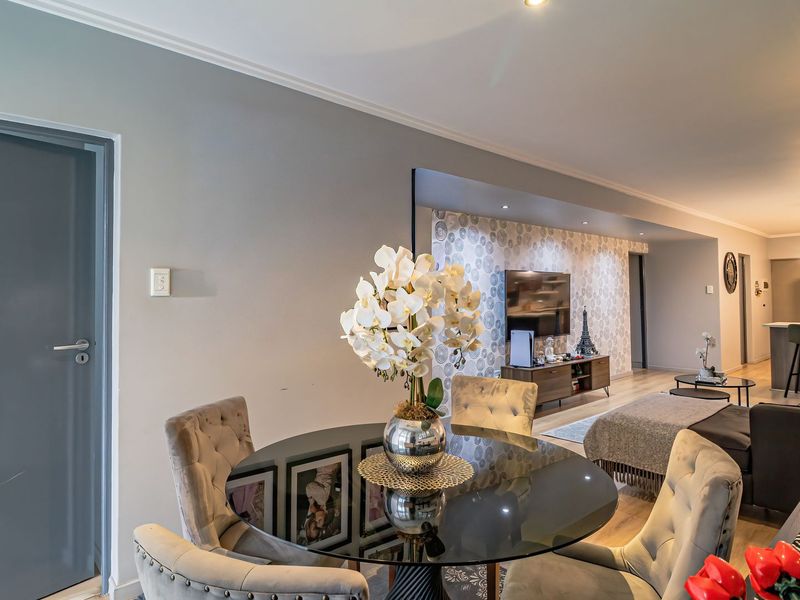 Spacious open-plan living and dining area featuring modern laminate flooring, recessed lighting, and a decorative feature wall.