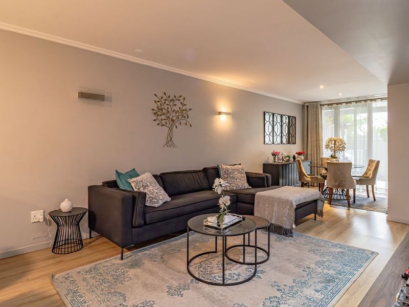 A well-maintained open-plan living and dining area featuring laminate flooring, modern lighting, and large sliding doors providing natural light.