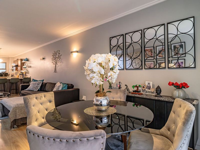 Spacious open-plan living and dining area featuring modern laminate flooring, contemporary wall lighting, and a well-integrated kitchen with island seating.