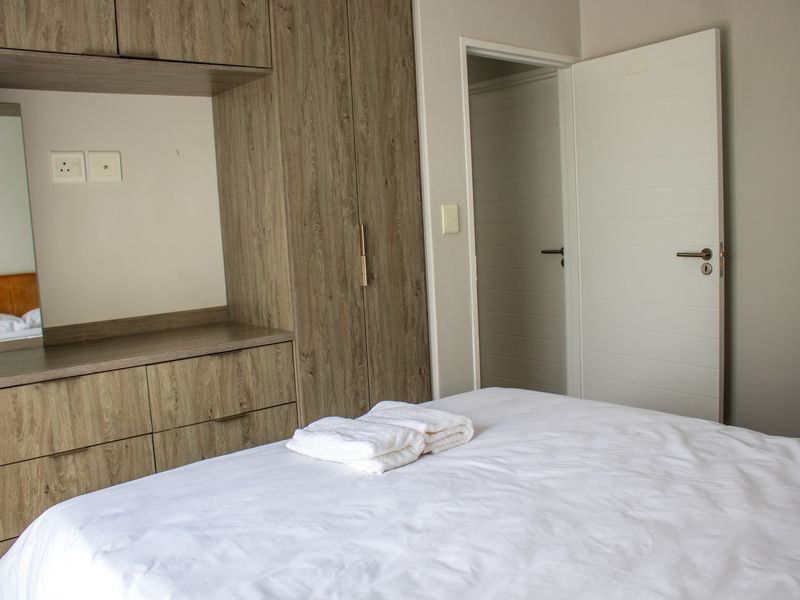 A well-maintained bedroom featuring modern wood-grain built-in cabinetry, integrated vanity, and a clean, neutral interior finish.