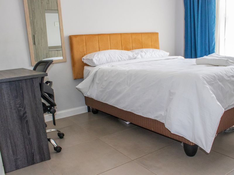 A well-lit bedroom featuring neutral tiled flooring and clean wall finishes, providing a comfortable and functional living space.