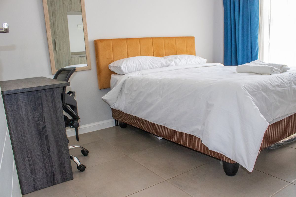 A well-lit bedroom featuring neutral tiled flooring and clean wall finishes, providing a comfortable and functional living space.