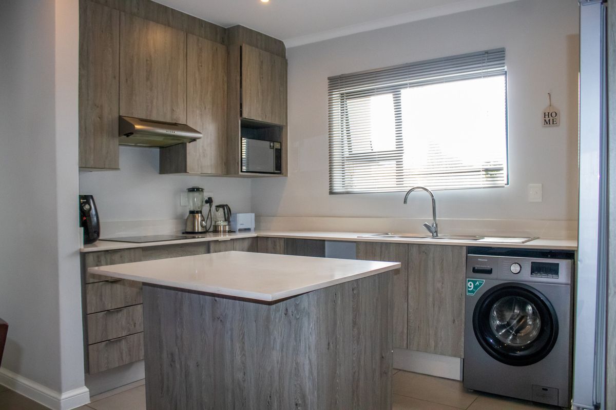 Modern kitchen featuring wood-look cabinetry, stone countertops, integrated appliances, and a functional island, providing a clean and contemporary cooking space.