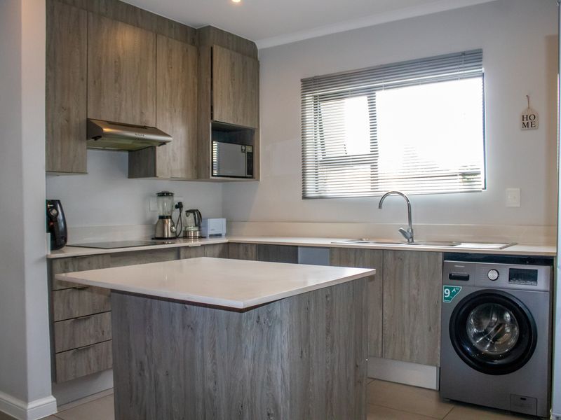 Modern kitchen featuring wood-look cabinetry, stone countertops, integrated appliances, and a functional island, providing a clean and contemporary cooking space.