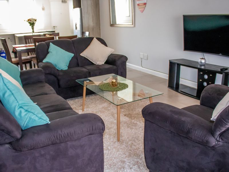Open plan living area featuring tiled flooring and neutral wall finishes, seamlessly connecting to the adjacent dining and kitchen space.