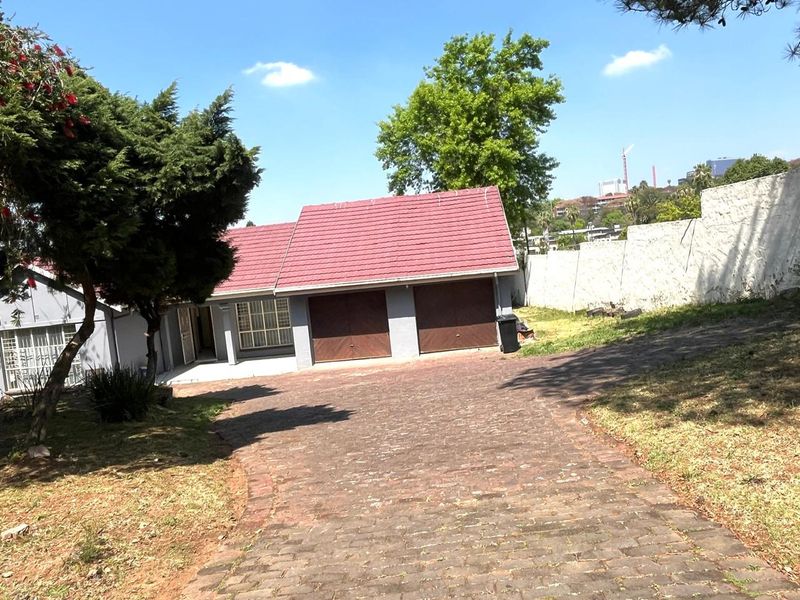 Front view of a residential property featuring a double garage, paved driveway, and perimeter boundary wall.