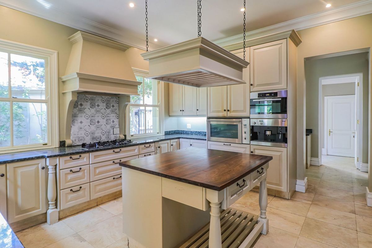 Spacious kitchen featuring classic cabinetry, granite countertops, a central island with a wooden top, and integrated high-end appliances.