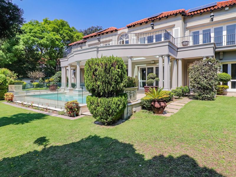 Rear view of a luxury cluster home featuring a swimming pool with glass fencing, a spacious terrace, and an upper-level balcony.