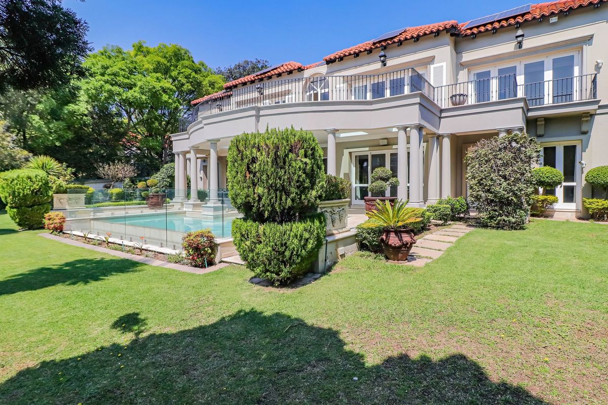 Rear view of a luxury cluster home featuring a swimming pool with glass fencing, a spacious terrace, and an upper-level balcony.