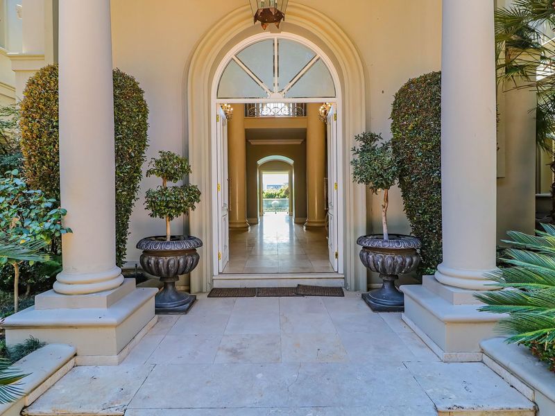 Grand entrance featuring an arched double door, stone columns, and elegant stone flooring, providing a welcoming and sophisticated transition into the home.
