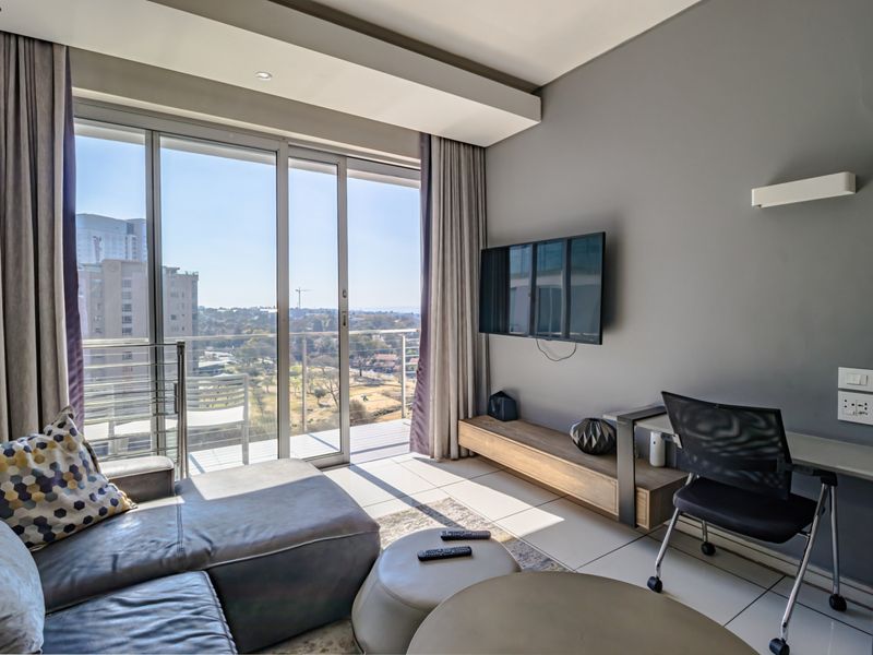 Modern living room featuring large sliding glass doors leading to a balcony, tiled flooring, and neutral wall finishes with integrated lighting.