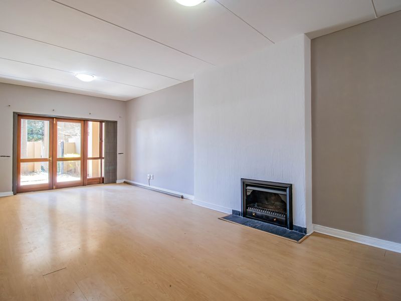 Spacious living room featuring laminate flooring, a built-in fireplace, and sliding glass doors providing access to the outdoor area.