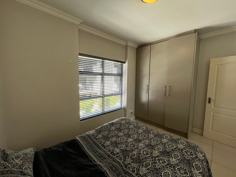 A well-maintained bedroom featuring neutral walls, tiled flooring, coving, and a large built-in wardrobe with modern finishes.